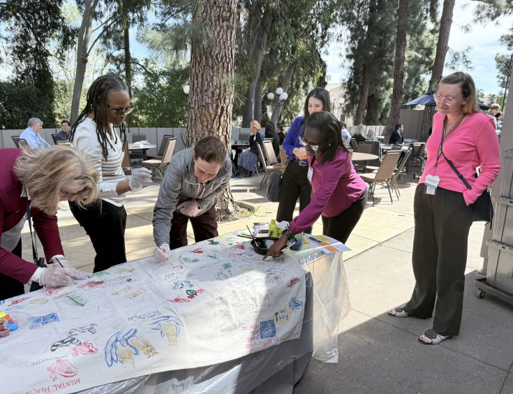 Symposium participants join in painting the mural.